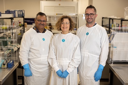 Three people standing together in a laboratory wearing white lab coats with the CSIRO logo on them.
