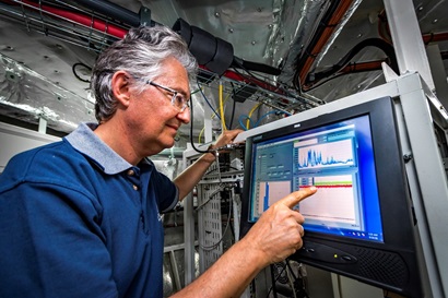 A scientist, Zoran Ristovski, in a laboratory onboard the Investigator, looking at a computer screen.