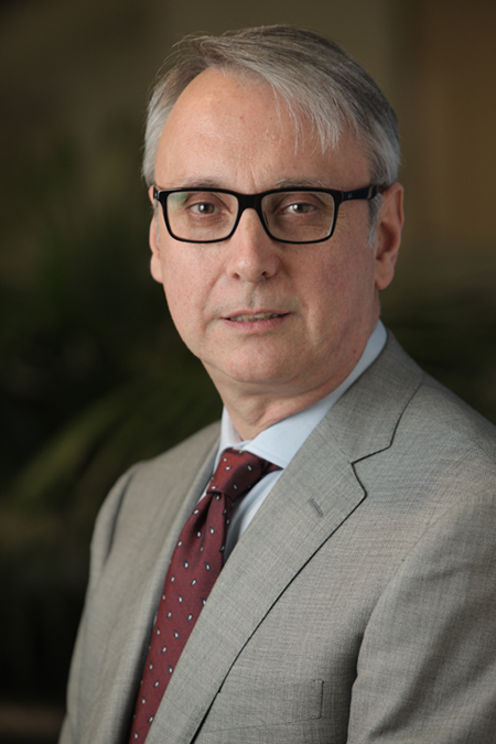 Dr Manuel Blanco, wearing a grey suit and black framed glasses.