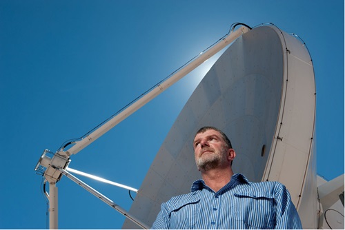 Dr Lewis Ball stands under a radio telescope.