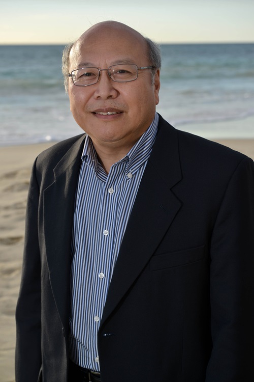 Portrait photo of Dr Ken Lee with beach and ocean as the backdrop.