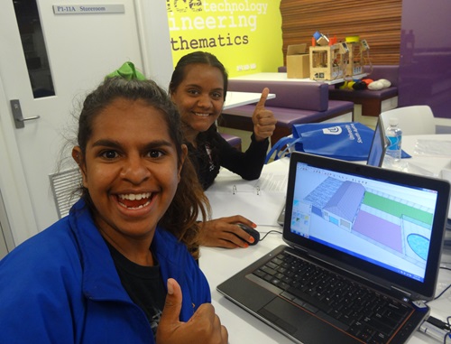 Smiling Indigenous students using a laptop