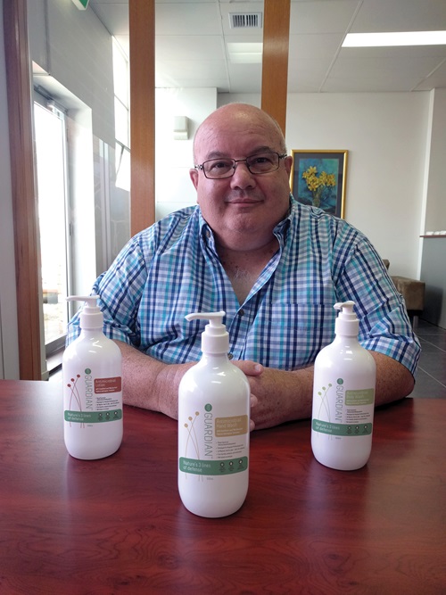 Frank Palermo sitting at a table behind bottles of Bio3 Guardian. 