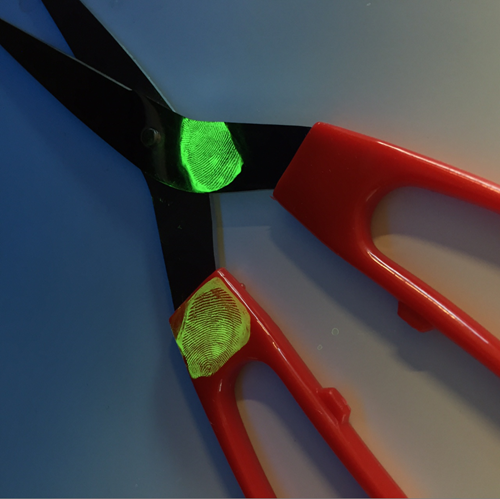 Glowing fingerprints on a pair of scissors.