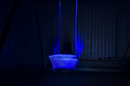 One seat of the Infinity swing glowing in blue light.