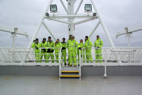 Scientists standing on the deck of the RV Investigator in fluro yellow cold water clothing.