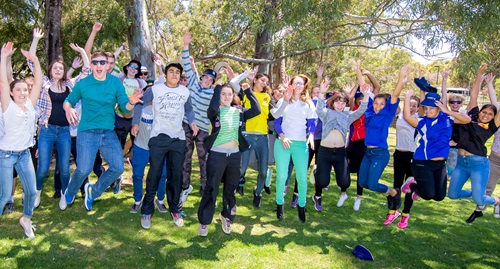 Group of people jumping off the ground with arms flung over their heads. 