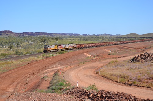 Train engines pulling dozens of freight wagons stretching behind into the distance.