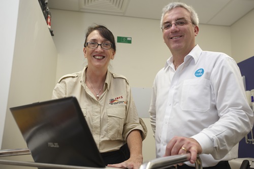 Ghislaine Wharton and David Hansen standing in fron tof a laptop.