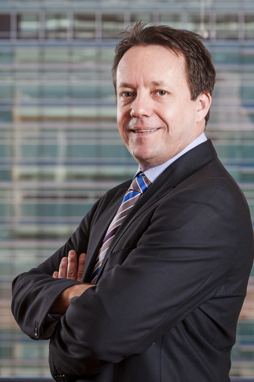 Dr Chris Chilcott with arms crossed in a jacket and tie