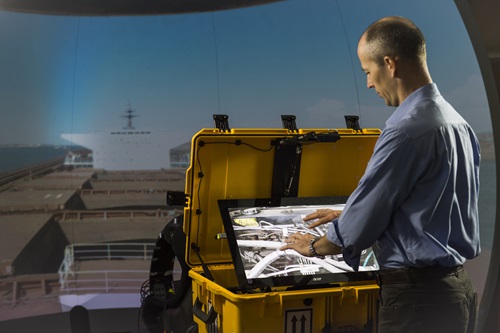 Man standing in front of display screen using hands to manipulate the image.
