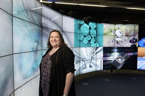 Person standing in front of a wall of electronic screens.