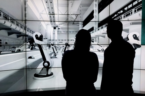 People silhouetted in front of a wall of electronic screens.