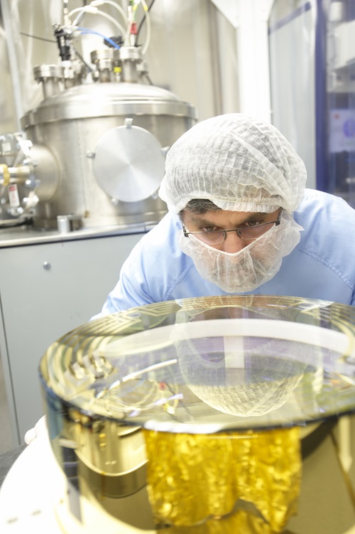 A scientist examining the gold electrodes deposited onto the cavity optics used in the Laser Interferometer Gravitational-Wave Observatory (LIGO).
