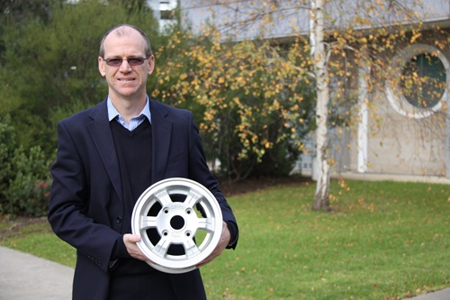 Dr Mark Cooksey holding a magnesium metal car wheel rim.