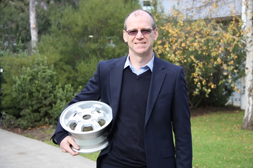 Dr Mark Cooksey holding a magnesium metal car wheel rim.