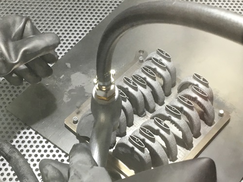 An air gun is used in the powder recovery system (PRS) to reveal the hidden devices within the titanium block.