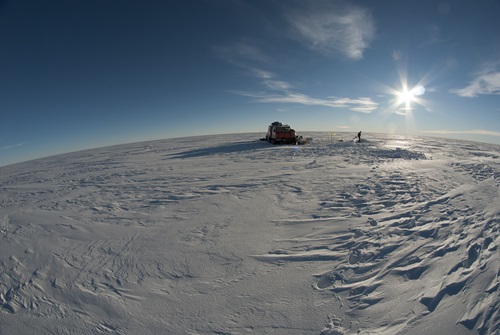 Snowy landscape with ice core drilling camp in the background.