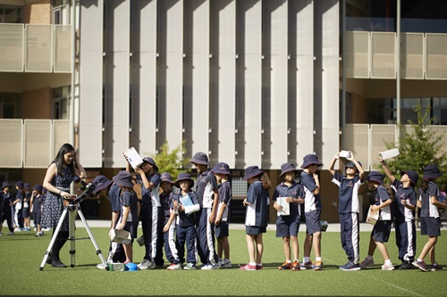 Scientist showing students how to use a telescope.