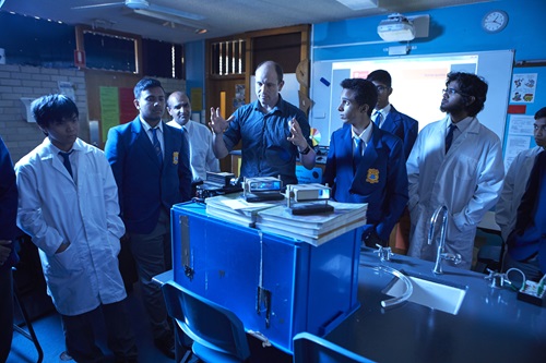 Students standing around lab equipment during a lesson. 