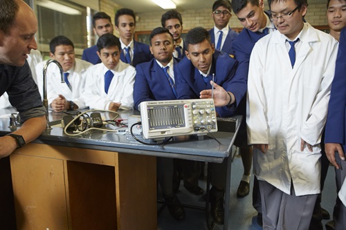 Students standing around lab equipment during a lesson. 