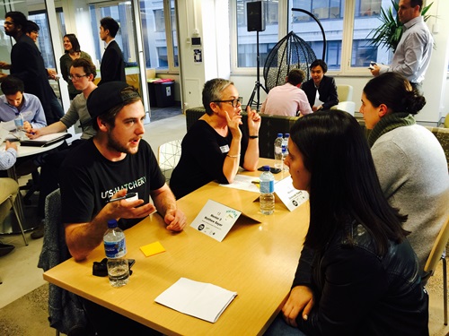 People sitting around tables discussing technology during a speed networking program.