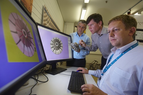 Scientists in front of computer screens with one holding a 3D printed object.