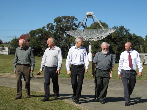 CSIRO's WLAN team in May 2012 walking together in front of a small radio telescope.