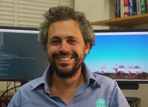 CSIRO’s Dr Keith Bannister foreground with computer screen in the background showing the ASKAP. 