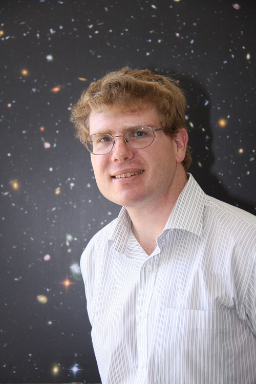 Dr Jean-Pierre Macquart standing in front of a backdrop showing a section of the night sky. 