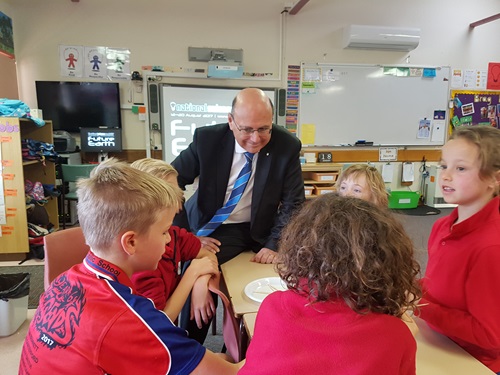 Senator the Hon Arthur Sinodinos AO sitting at a table talking to Gundaroo primary students about science during our STEM in Schools event.