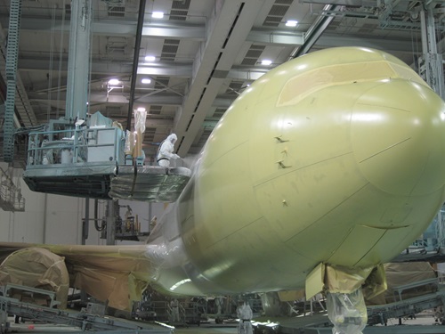 A large commercial aircraft is painted in a hanger.