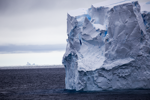 Side view of a large iceberg floating on the ocean.