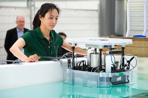 A woman works with a robotic device in a water tank.
