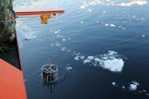 Sampling equipment being lowered over the side of a ship.