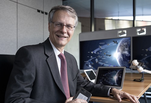 Dr Alex Held sitting at a desk with computer screens in the background. 