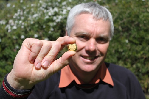 Scientist Paul Breuer holds up a one-ounce commemorative gold ingot engraved with the CSIRO logo.