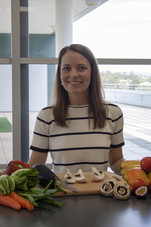 Jessica Bogard standing at a bench with fresh fruit and vegetables. 