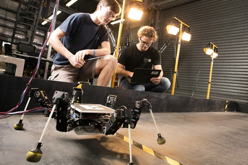 Researchers studying a six legged robot.