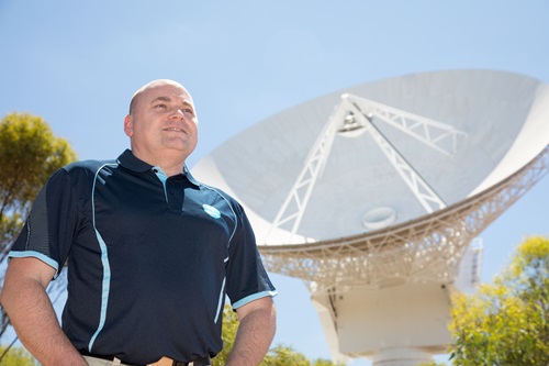 Person standing in front of a radio telescope. 