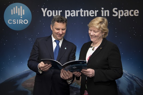 Dr Larry Marshall and Dr Megan Clark standing in front of an earth from space posterlooking at copies of the space roadmap. 