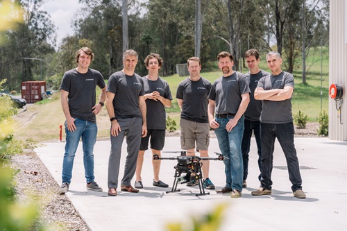 The Emesent team standing outside behind a drone on the ground. 