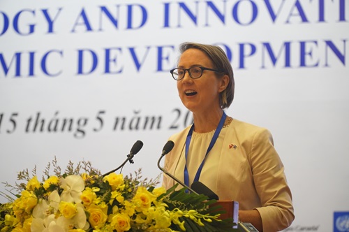 Dr Lucy Cameron presenting the report at a podium with yellow flowers on the front. 