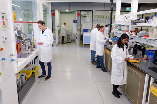 Scientists stand at laboratory benches