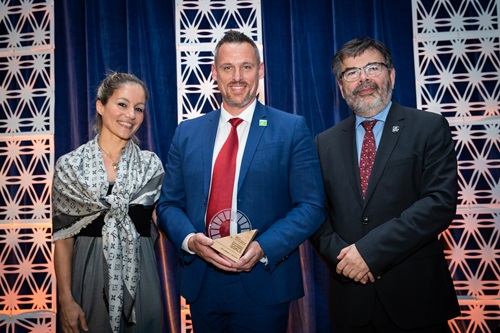 Three people on stage, one holding award