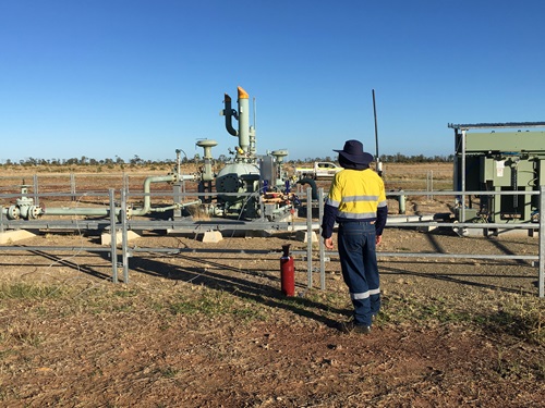 Person in workwear standing at a coal seam gas well.