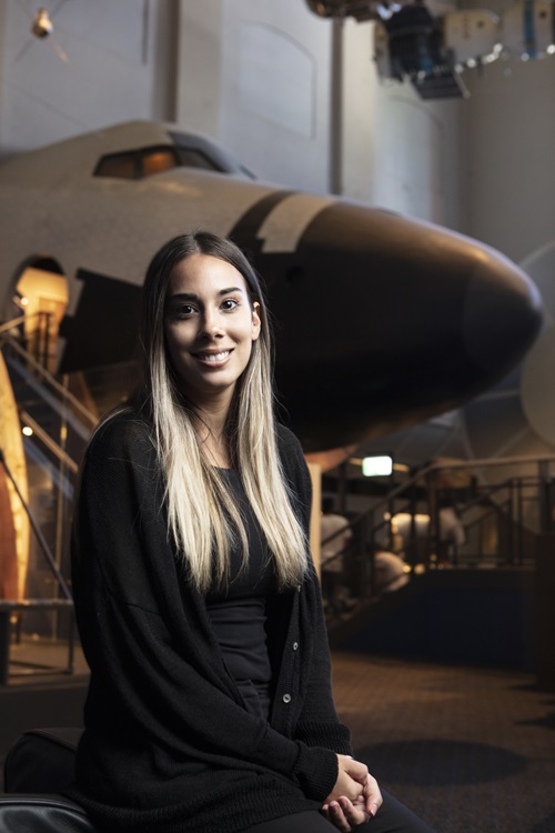 Taylah Griffin posing in front of the nose of an aeroplane.