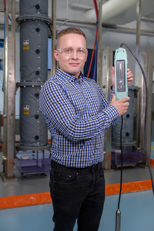 Person holding part of the Vesi monitoring equipment in a plant room. 