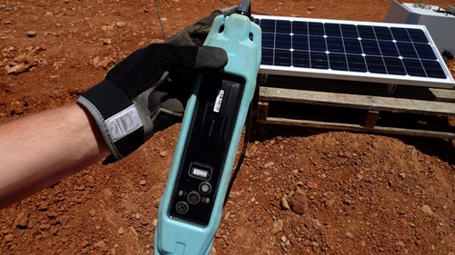 Hand holding the SENSEI multi-sensor array with a solar panel in the background. 