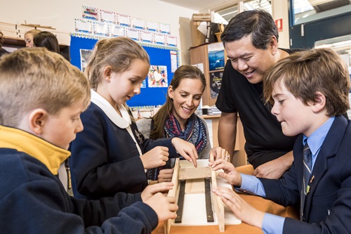 Primary school students and adults around a science experiment